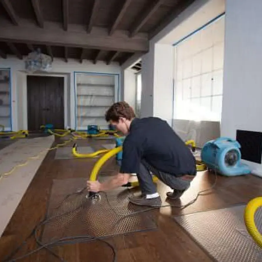 Restoration tech setting a drying mat on a wet hardwood floor in a Huntersville home