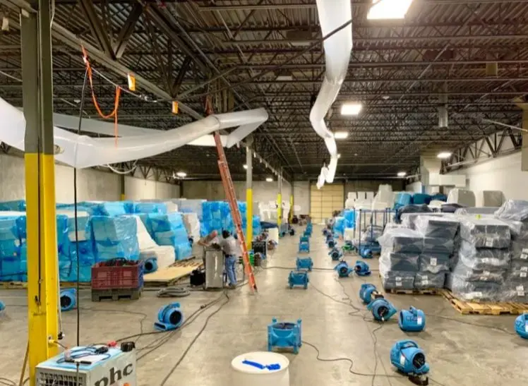 Air movers and dehumidifiers drying a large commercial warehouse floor