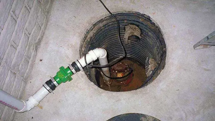 Open sump pit with a failed pump and discharge pipe in a Huntersville basement